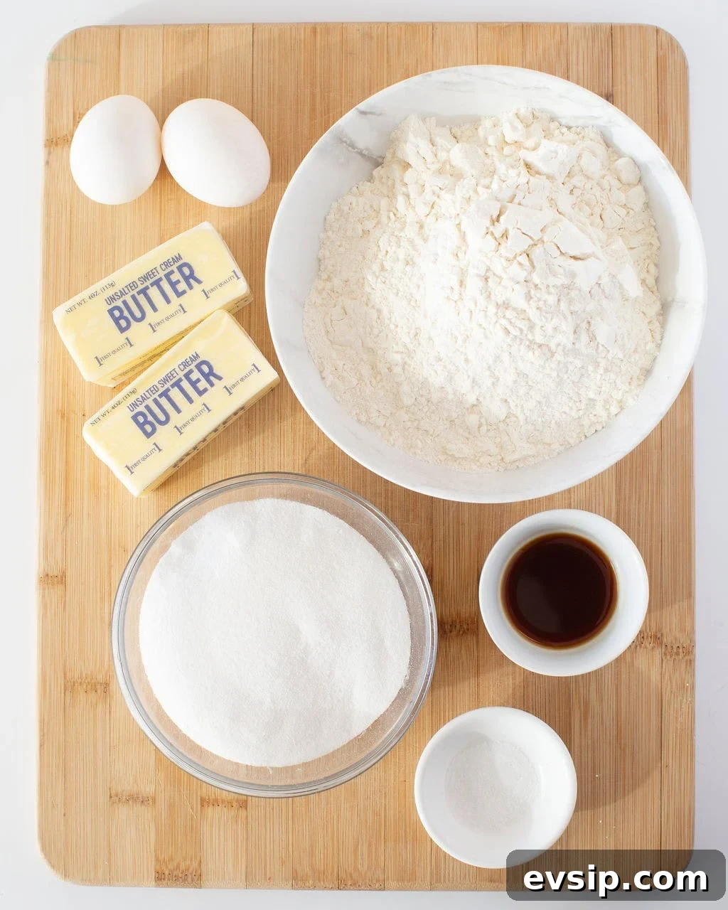 Ingredients to make sugar cookies on a wooden cutting board. 
