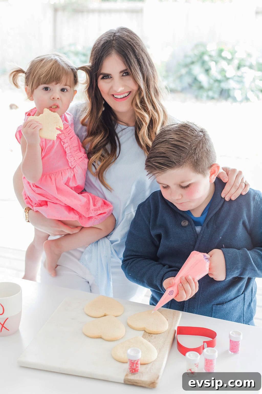 A mother and her small children decorating cookies. 
