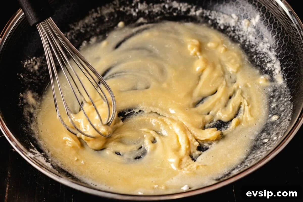 How to Make Turkey Stock A whisk mixing a roux in a shallow pan.