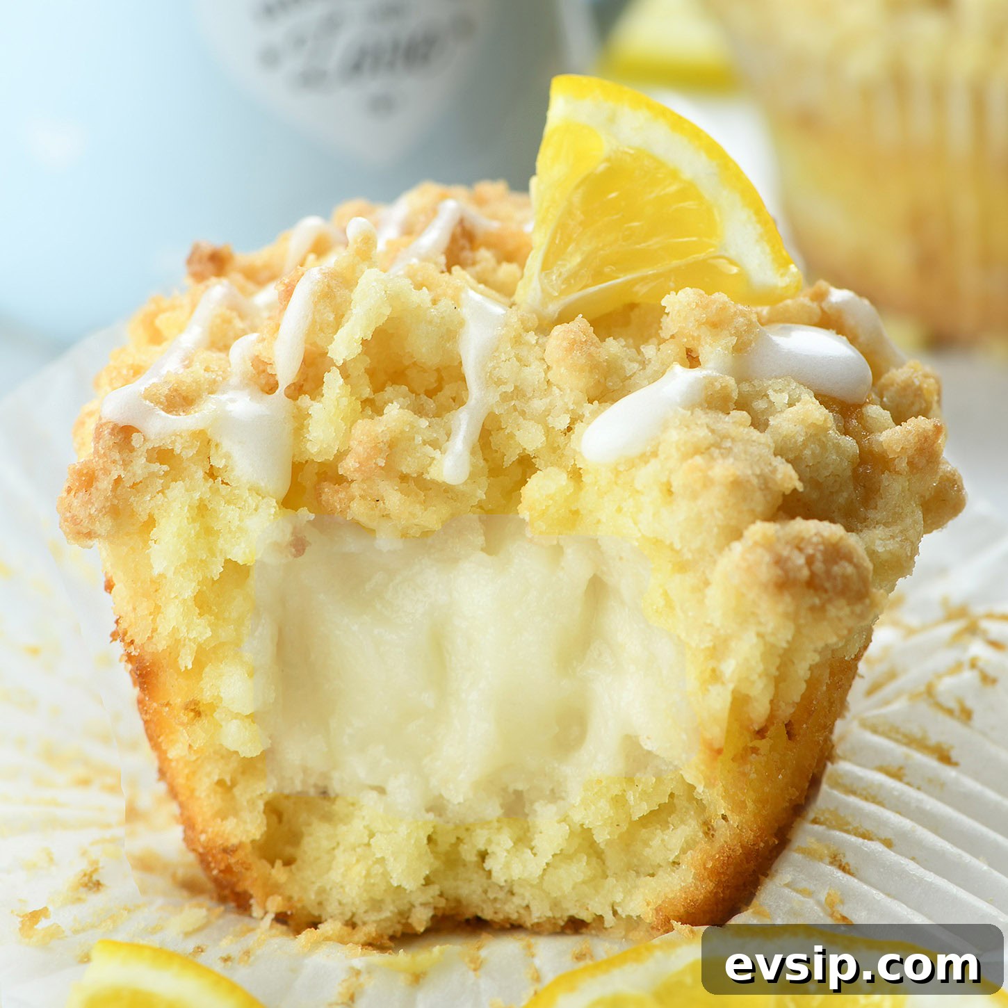 lemon muffin with cream cheese filling and crumb topping close up with glaze drizzle