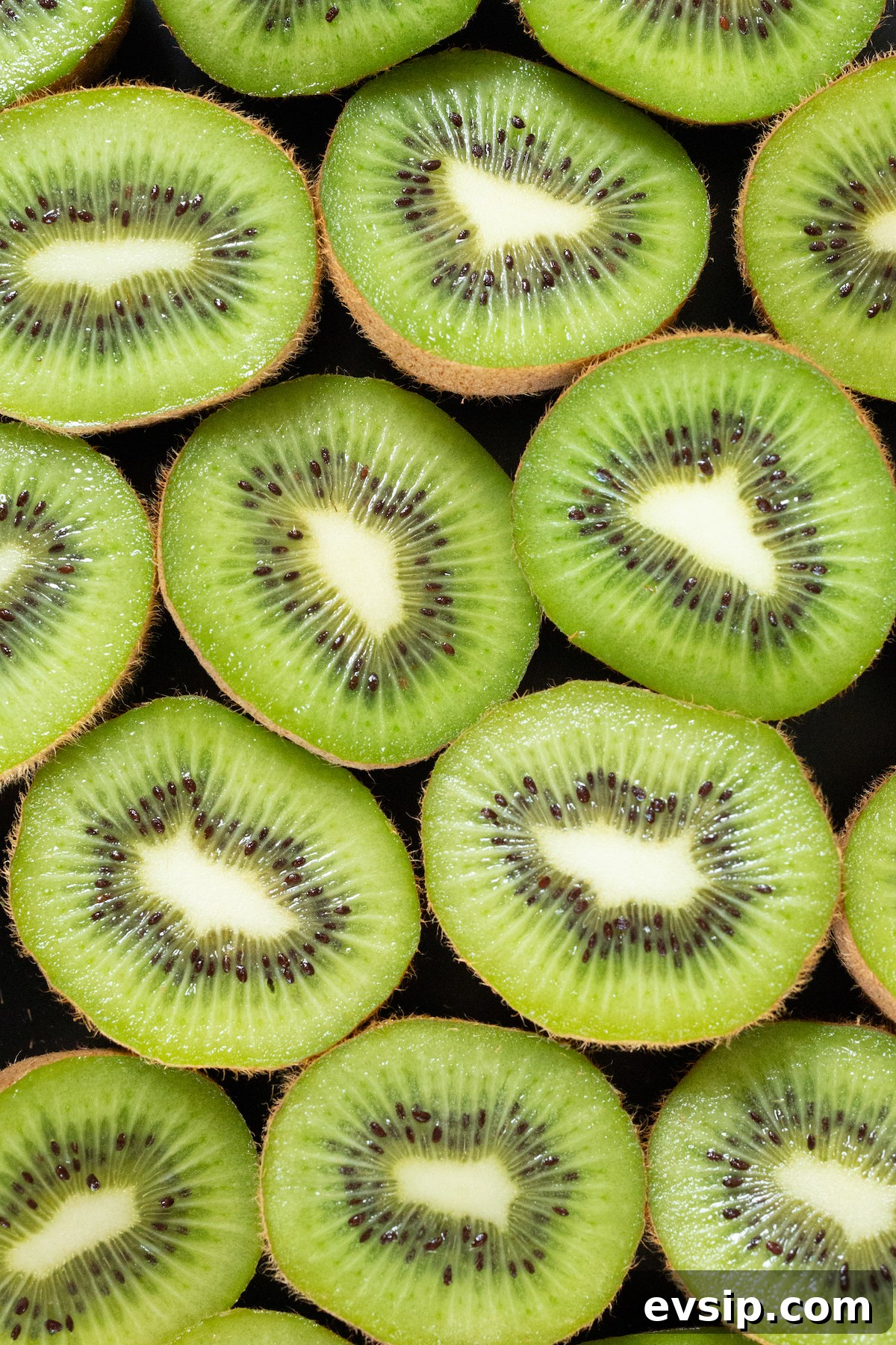 How to Make Dehydrated Kiwi Slices at Home 4 Overhead look at about a dozen of green kiwis that have been sliced in half.