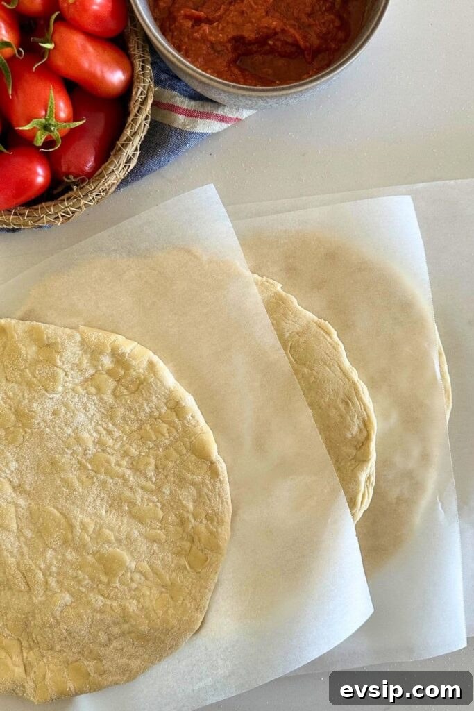20 Sourdough Discard Recipes Perfect for Freezing 11 4 sourdough discard pizza bases separated by pieces of parchment paper.