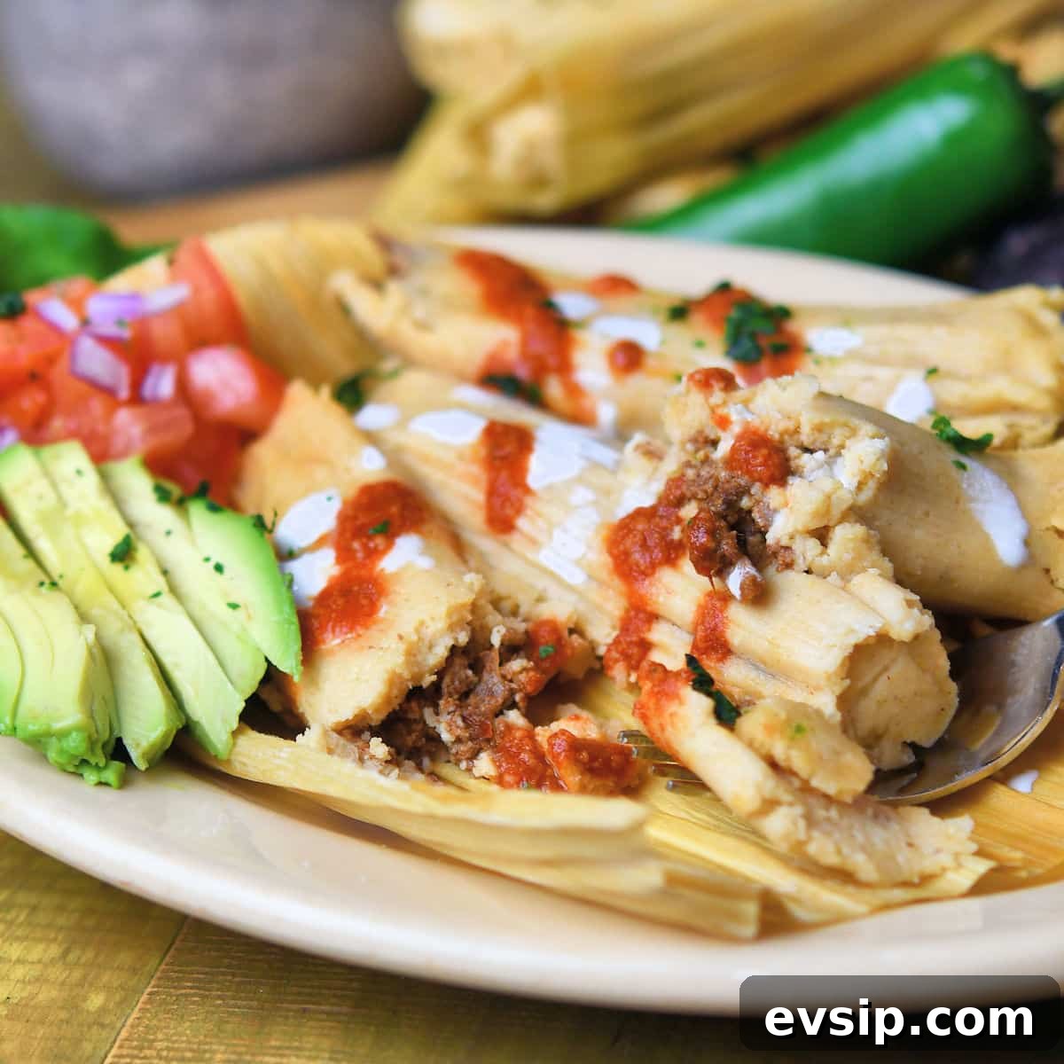 pork tamales on an oval plate with avocado and tomato salsa