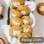 8 pumpkin cheesecake cookies in rectangular dish surrounded by fall decor.