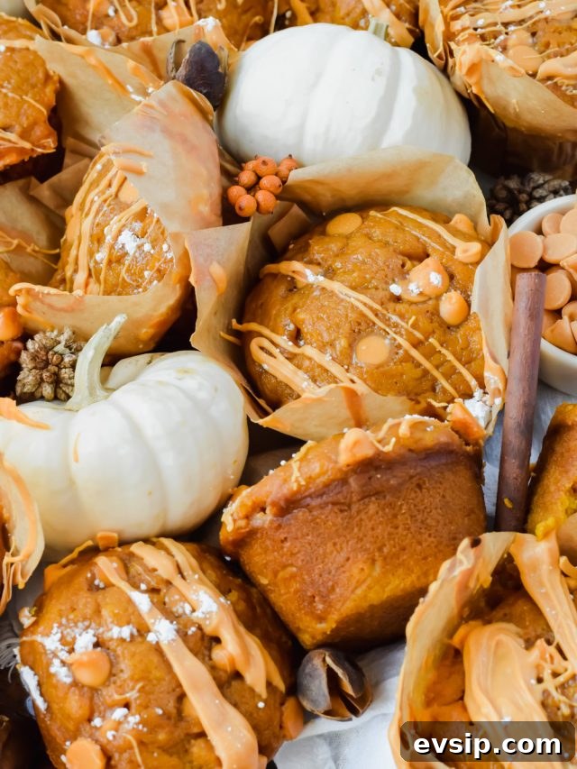 butterscotch pumpkin muffins drizzled with melted butterscotch and dusted with powdered sugar piled together with mini white pumpkin decorations scattered between.