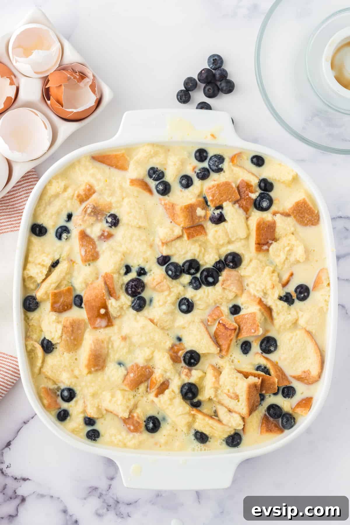 Lemon Blueberry Bread Pudding Recipe 6 Unbaked lemon blueberry bread pudding in square casserole dish.