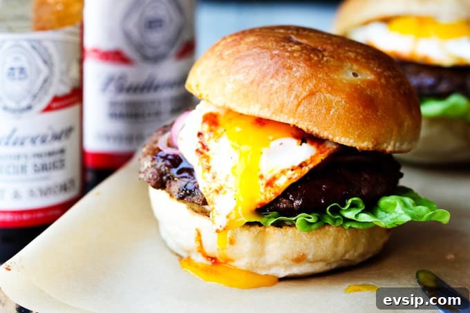 Smoky BBQ Burger with Garlic Aioli and Fried Egg Recipe 7 Smoky BBQ burger with runny egg yolk and sauces in the back